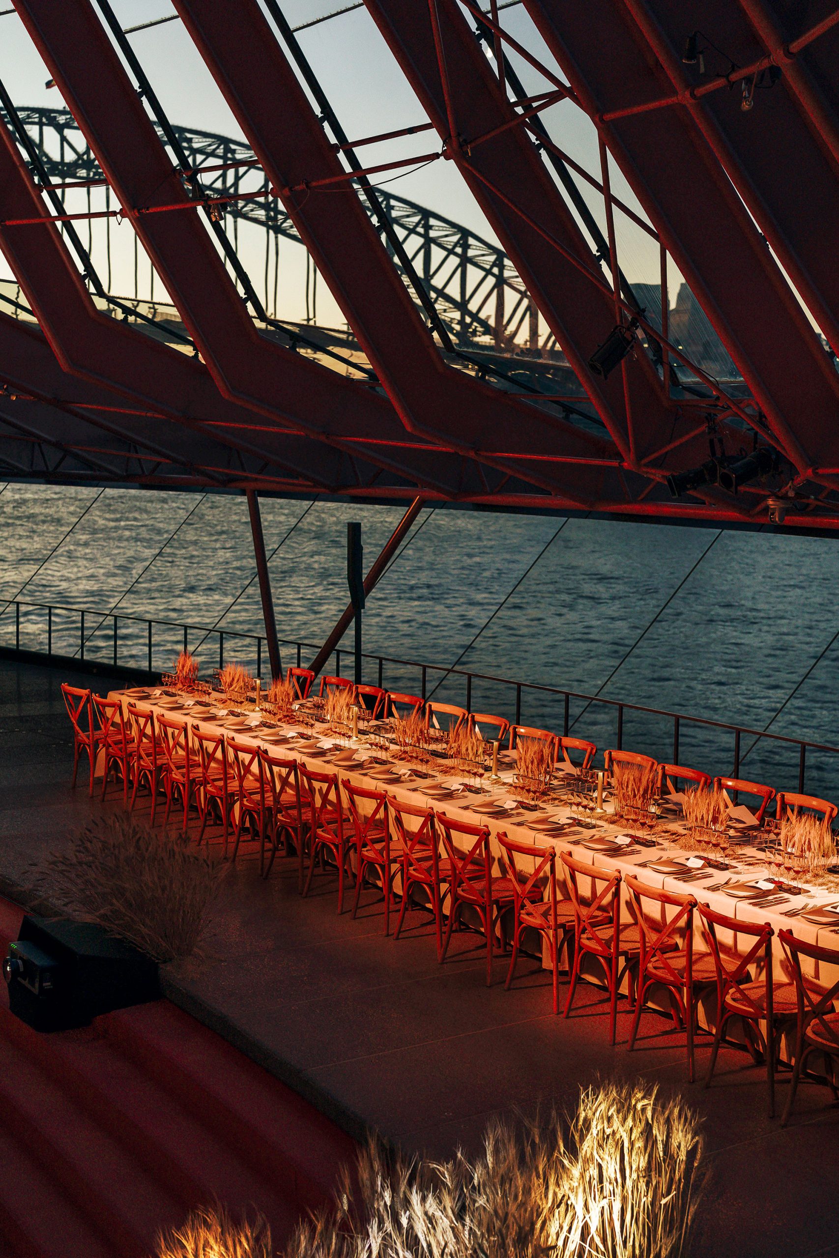 Long table event set up inside of the Sydney Opera House with a view of the Sydney Harbour Bridge